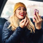 a young woman putting make-up on in a car